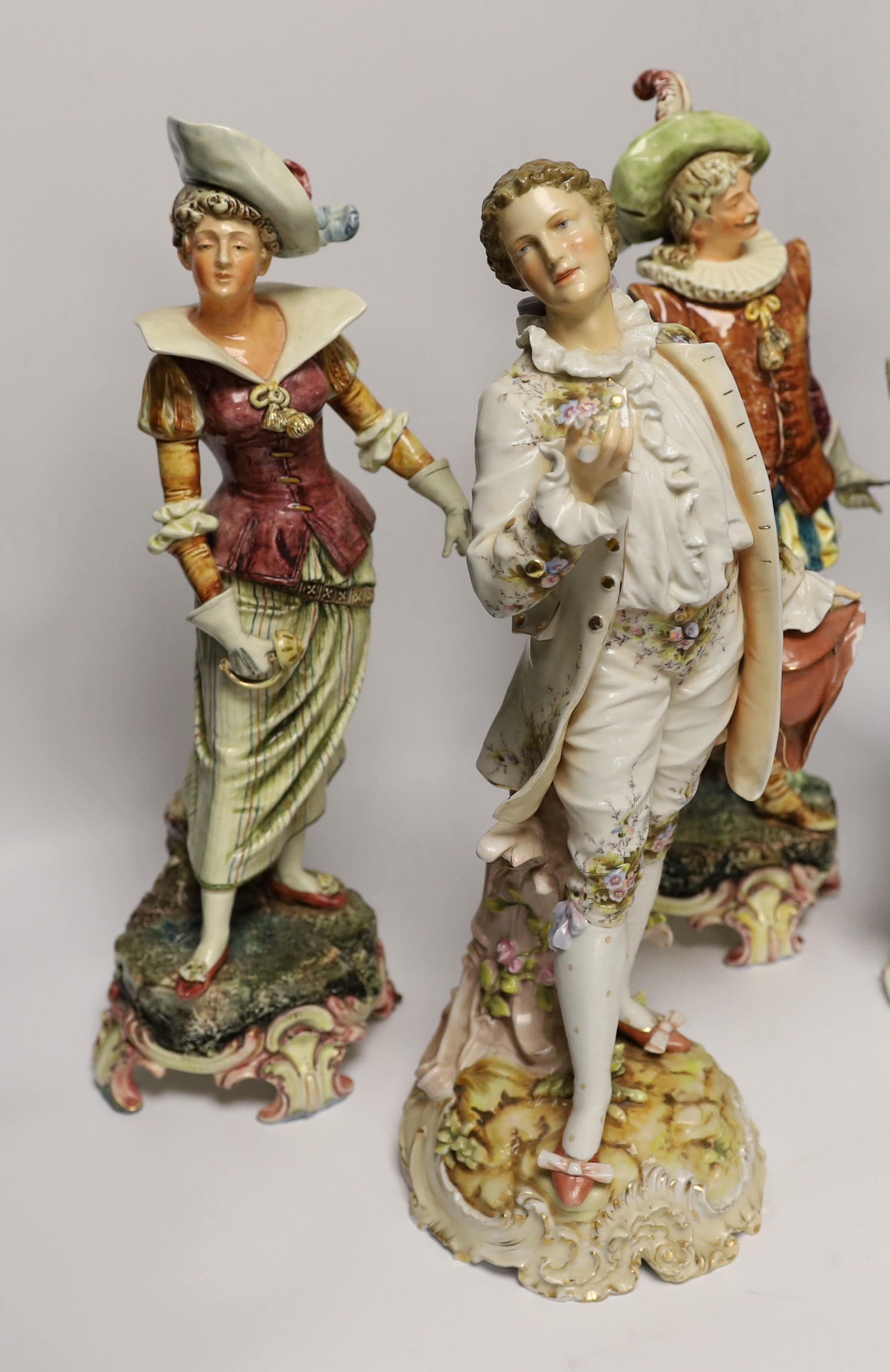A pair of Volkstedt porcelain figures and a pair continental earthenware figures, 42cm